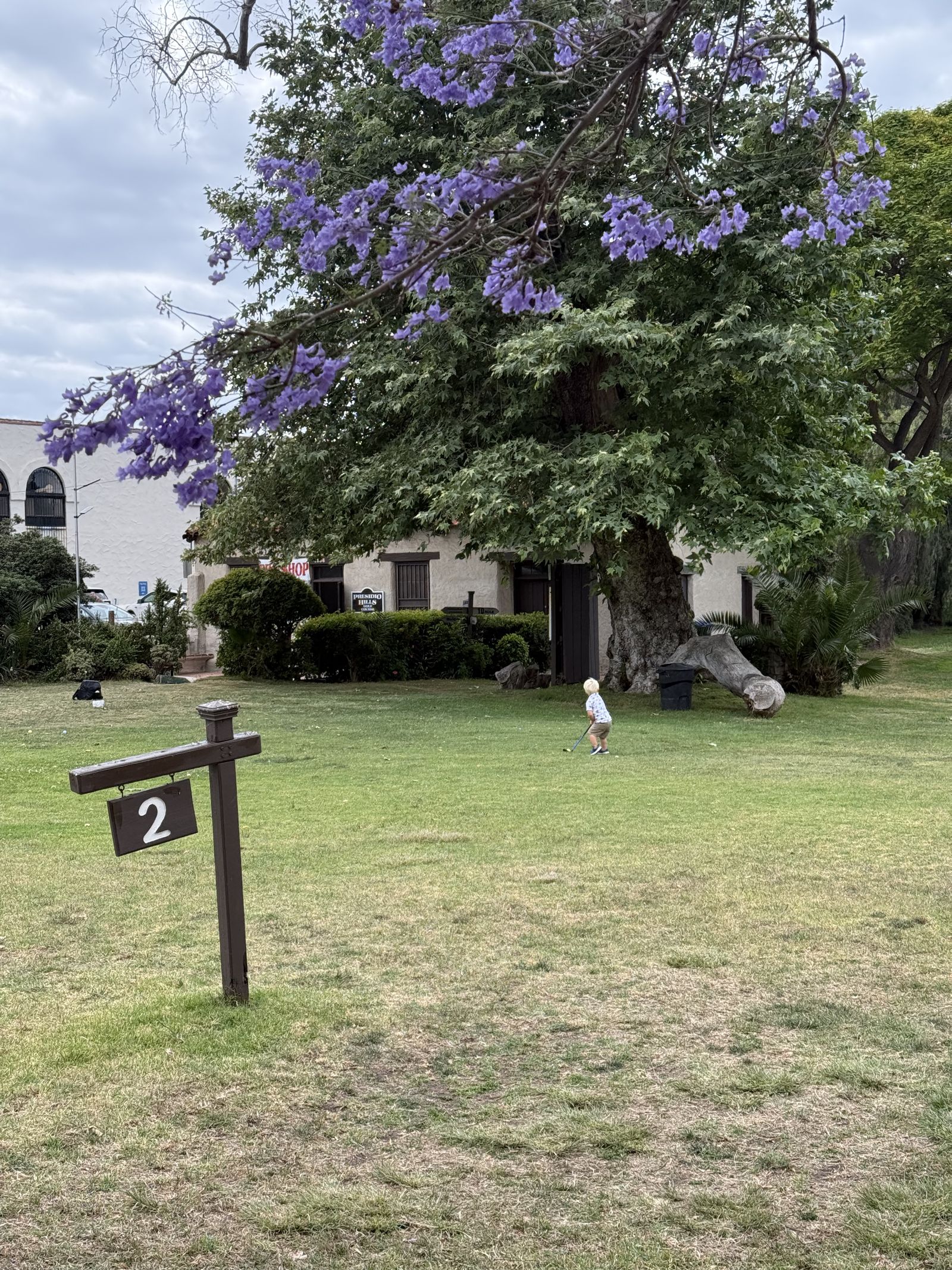 The adobe clubhouse and a giant shade tree by the second hole marker